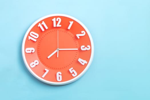 beautiful Orange wall clock on blue background ,concept of Start the morning to work.