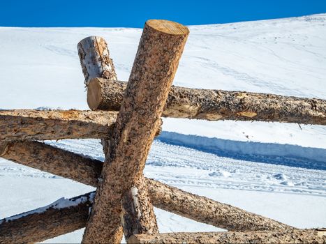 A man made wooden fence sits on the slopes of the Rocky Mountains.