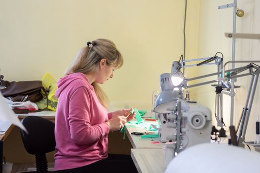 Professional seamstress makes an element of clothing in the workplace