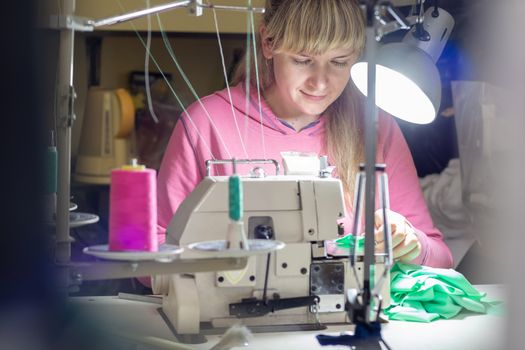 Girl works by light lamp behind industrial sewing machine