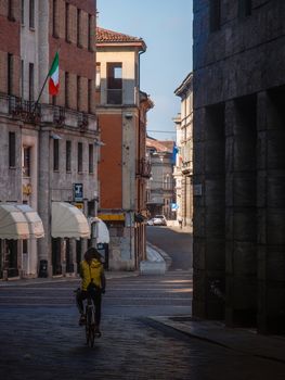 Cremona, Lombardy, Italy - May  5 6 7  2020 - man or woman walking or biking in deserted downtown  during covid outbreak lockdown phase 2