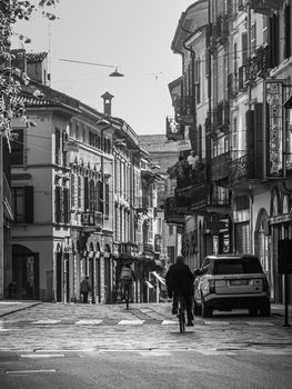 Cremona, Lombardy, Italy - May  5 6 7  2020 - man or woman walking or biking in deserted downtown  during covid outbreak lockdown phase 2