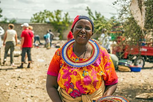 MTO WA MBU, ARUSHA, TANZANIA - OCTOBER 22, 2014 : Traditionally dressed african woman from the masai tribe selling merchandise in the Masai Central Market of Mto Wa Mbu.