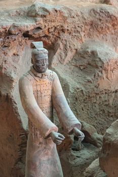 Xian, China - May 1, 2010: Terracotta Army museum and hall.  Gray-beige ancient soldier offering hands sculpture at excavation.