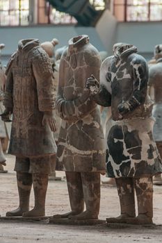 Xian, China - May 1, 2010: Terracotta Army museum and hall.  3 gray-beige sculptures of decapitated soldiers at excavation.