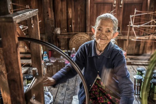 INLE LAKE, MYANMAR - JANUARY 26, 2016 : Woman worker weaves fabric in a weaving factory on Inle Lake.
