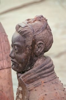 Xian, China - May 1, 2010: Terracotta Army museum and hall.  Side face closeup on gray-red sculpture of soldier at excavation.