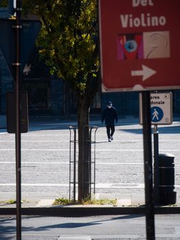 Cremona, Lombardy, Italy - May  5 6 7  2020 - man or woman walking or biking in deserted downtown  during covid outbreak lockdown phase 2