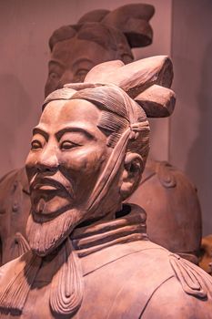 Xian, China - May 1, 2010: Terracotta Army museuml.  Side Closeup of reddish bearded head of officer sculpture with another one in faded back.