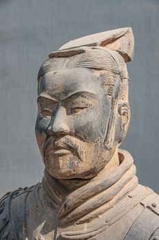 Xian, China - May 1, 2010: Terracotta Army museum. Face closeup of higher officer beige-gray sculpture outside buildiing. Gray wall as backdrop.