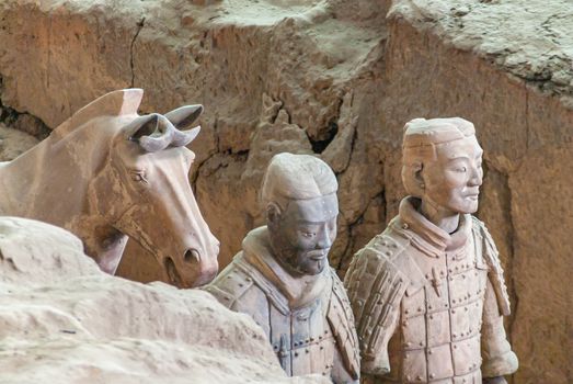 Xian, China - May 1, 2010: Terracotta Army excavation site. Chest closeup of 2 Beige-gray statues of soldiers standing with horse in trench.