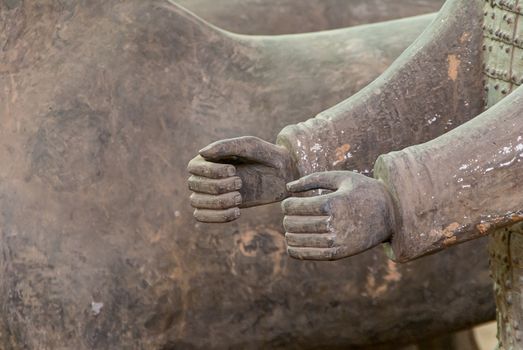 Xian, China - May 1, 2010: Terracotta Army excavation site. Closeup of 2 beige-gray human hands. Horse body as backdrop.