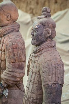 Xian, China - May 1, 2010: Terracotta Army excavation site. Side chest closeup of beige-gray sculpture of soldier.