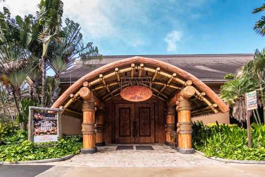 Laie, Oahu, Hawaii, USA. - January 09, 2020: Polynesian Cultural Center. Large wooden entrance to Island Buffet restaurant under blue sky with lots of green vegetation and foliage around.