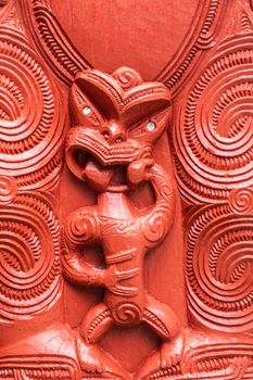 Laie, Oahu, Hawaii, USA. - January 09, 2020: Polynesian Cultural Center. Closeup of detail of red wooden sculpture showing small scary figure at New Zealand Maori hawaikiroa hall.