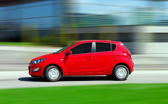 A panning shot of a speeding small red car