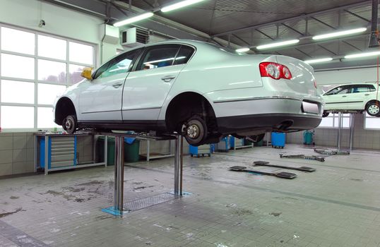 Car on base plate of lift in workshop