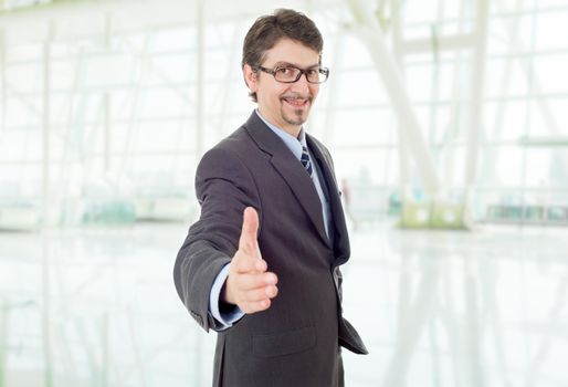 businessman in suit offering to shake the hand, at the office