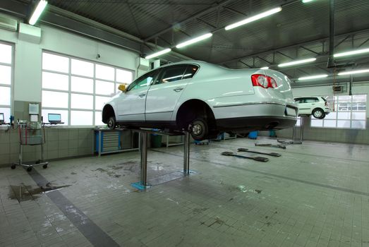 Car on base plate of lift in workshop