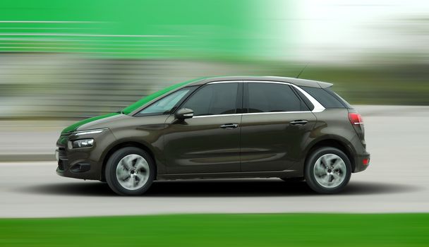 A panning shot of a speeding brown car