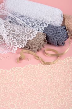 Roll of Delicate color laces for panties and bras on pink background with plastic fittings. Elastic material. Using for Atelier and fabric store.