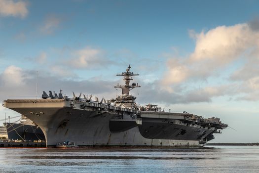 Oahu, Hawaii, USA. - January 10, 2020: Pearl Harbor. Gray Abraham Lincoln aircraft carrier docked under blue cloudscape on top of gray and blue water.