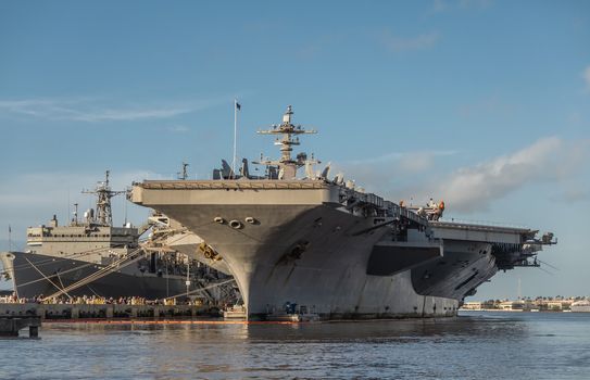 Oahu, Hawaii, USA. - January 10, 2020: Pearl Harbor. Gray Abraham Lincoln aircraft carrier docked with USNS Arctic in back under blue cloudscape on top of gray and blue water.