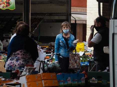 Cremona, Lombardy, Italy - 16 th may 2020 - People grocery shopping socially distance d in local biologic open air  food market wearing protection facial mask to prevent against contagion of coronavirus infection disease