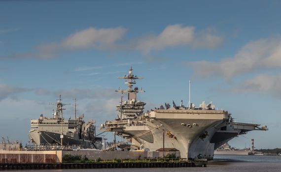 Oahu, Hawaii, USA. - January 10, 2020: Pearl Harbor. Gray Abraham Lincoln aircraft carrier docked with USNS Arctic in back under blue cloudscape on top of gray and blue water.