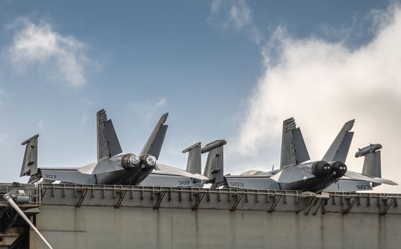 Oahu, Hawaii, USA. - January 10, 2020: Pearl Harbor. Fighter jets on deck of Gray Abraham Lincoln aircraft carrier docked under blue cloudscape.