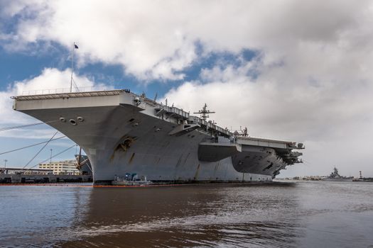 Oahu, Hawaii, USA. - January 10, 2020: Pearl Harbor. Under bow of Gray Abraham Lincoln aircraft carrier docked under blue cloudscape.