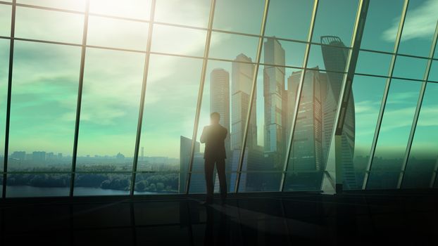 A silhouette of a businessman is standing against an office window with a view of the business center.