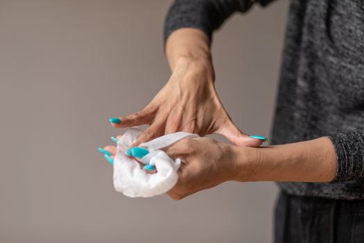 Old woman gently cleaning hands with wet wipes, white