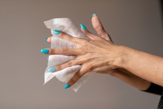 Old woman gently cleaning hands with wet wipes, white