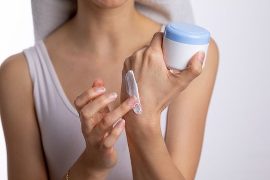 Young woman applying hand cream to protect and care skin, close up.