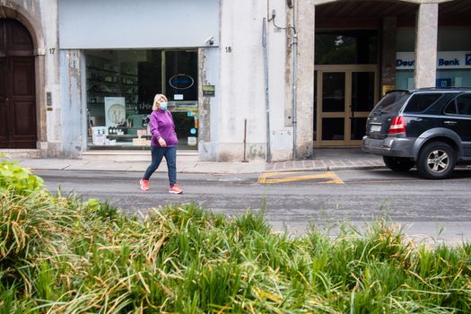 Cremona, Lombardy, Italy - May  5 6 7  2020 - man or woman walking or biking in deserted downtown  during covid outbreak lockdown phase 2