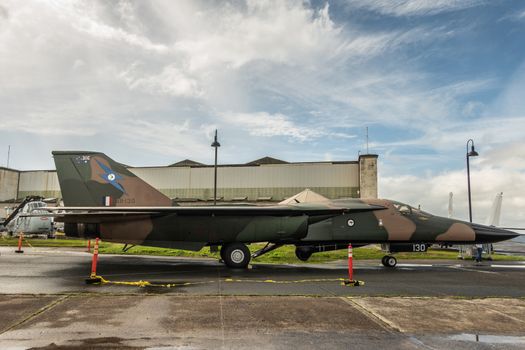 Oahu, Hawaii, USA. - January 10, 2020: Pearl Harbor Aviation Museum. Original Genral Dynamics F-111C model A8-130 fighter jet on tarmac near hangar under blue cloudscape. RAAF owned.