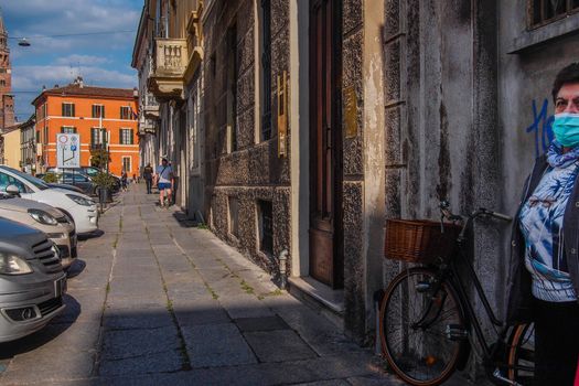 Cremona, Lombardy, Italy - May  5 6 7  2020 - man or woman walking or biking in deserted downtown  during covid outbreak lockdown phase 2