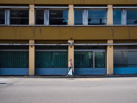 Cremona, Lombardy, Italy - May  5 6 7  2020 - man or woman walking or biking in deserted downtown  during covid outbreak lockdown phase 2