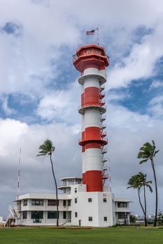 Oahu, Hawaii, USA. - January 10, 2020: Pearl Harbor Aviation Museum. Red and white control or watch tower of adjacent historic airfield under blue cloudscape. Green lawn and foliage.