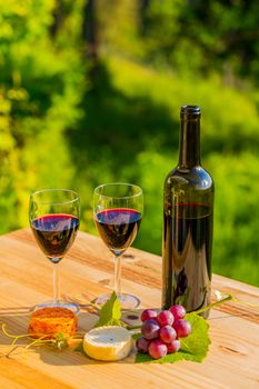 wine bottle and grapes on wooden table, outdoor