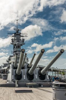 Oahu, Hawaii, USA. - January 10, 2020: Pearl Harbor. Multiple guns on bow and tower of USS Missouri Battle Ship under blue cloudscape. People on deck.