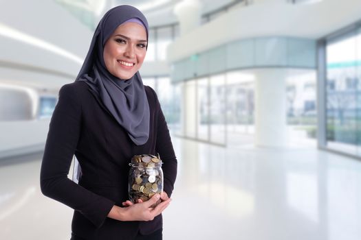 Pretty Muslim business woman hold coins in jar glass. Finance, investment, saving and insurance conceptual