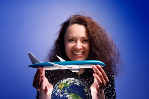 Girl with an airplane model in her arms over an earth globe. Concept of Airline help