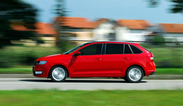 A panning shot of a speeding red car