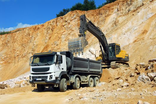 Yellow excavator loading stones in a truck