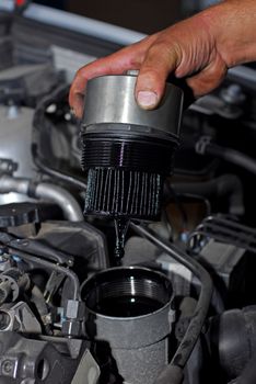 Repairman holding the old oil filter by car