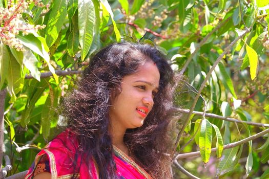 a gorgeous young woman standing in the autumn garden with hair flying in the wind