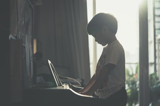 Little Boy is playing with piano and Music Tablet at home