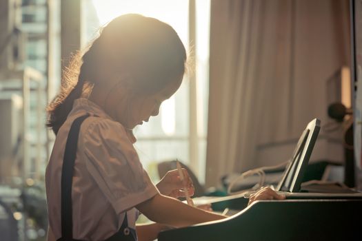 Little girl is playing with piano and Music Tablet at home
